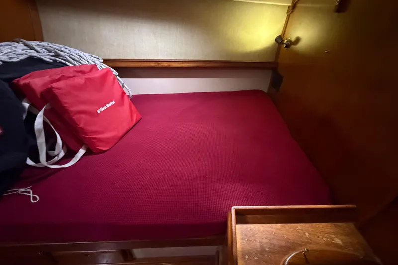 Slide: The Image of Cozy cabin interior of 1990 Island Packet 38 sailboat with red bedding and storage. - 17