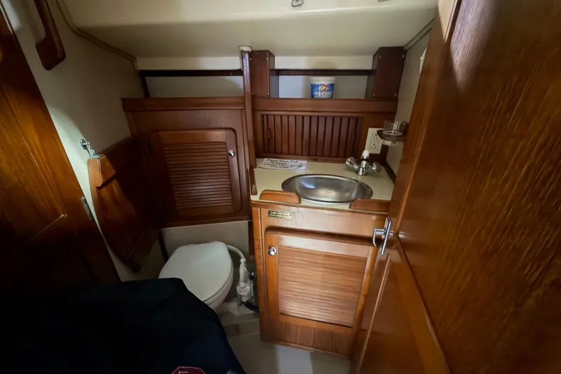 Slide: The Image of 1990 Island Packet 38 yacht bathroom with wooden cabinetry and stainless steel sink. - 18