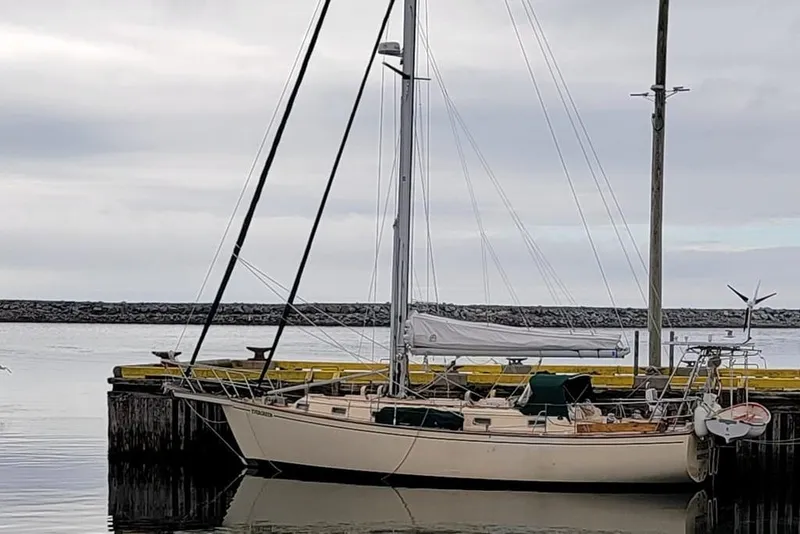 Slide: The Image of 1990 Island Packet 38 sailboat docked at a marina under cloudy skies. - 2