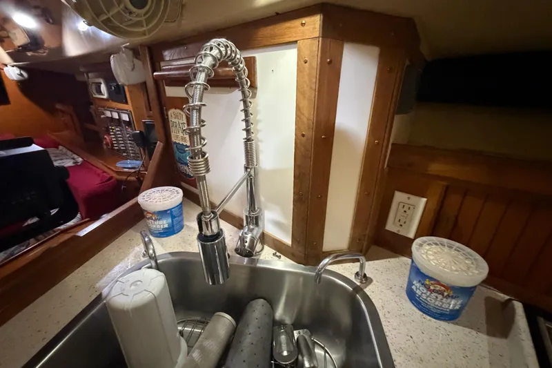 Slide: The Image of Interior of a 1990 Island Packet 38 sailboat, featuring a modern kitchen sink and faucet. - 23