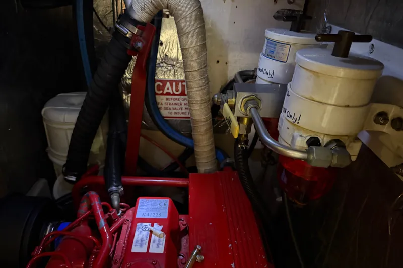 Slide: The Image of Engine compartment of a 1990 Island Packet 38 sailboat, featuring fuel filters and hoses. - 29