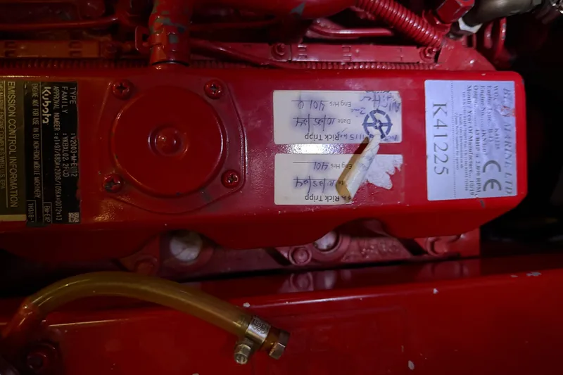 Slide: The Image of Red engine compartment of a 1990 Island Packet 38 sailboat, featuring labels and tubing. - 30