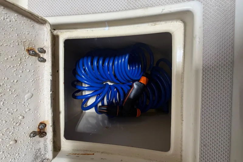Slide: The Image of Coiled blue hose in storage compartment of 1990 Island Packet 38 sailboat. - 48