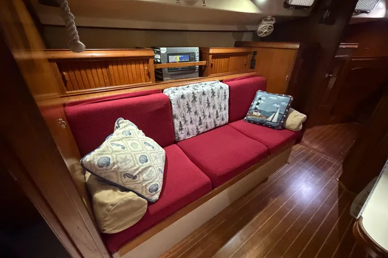 Slide: The Image of Interior of 1990 Island Packet 38 sailboat with red cushioned seating and decorative pillows. - 5
