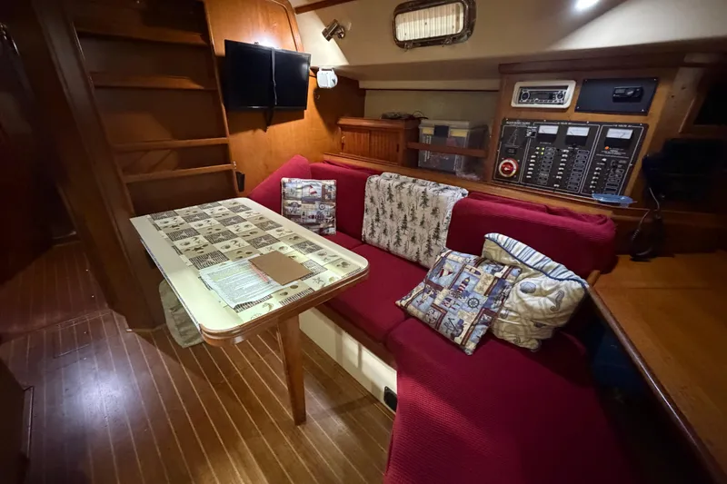 Slide: The Image of Cozy interior of 1990 Island Packet 38 sailboat with red seating and nautical-themed decor. - 6