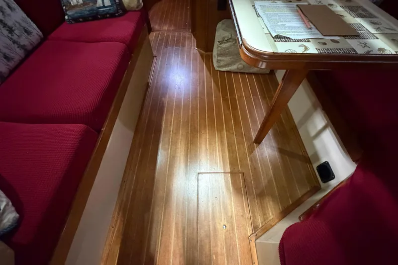 Slide: The Image of Interior of 1990 Island Packet 38 sailboat with red seating and wooden flooring. - 7
