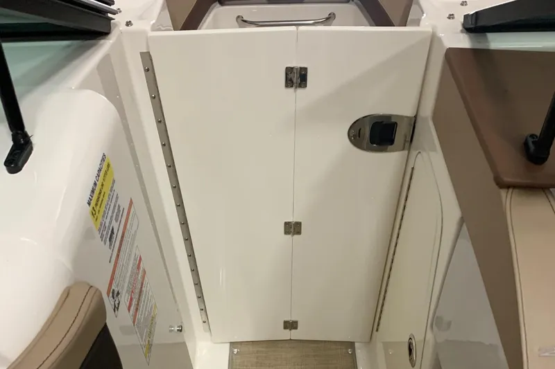 Slide: The Image of Interior view of a Sea Ray 240 Sundeck with a white door and brown seats. - 22