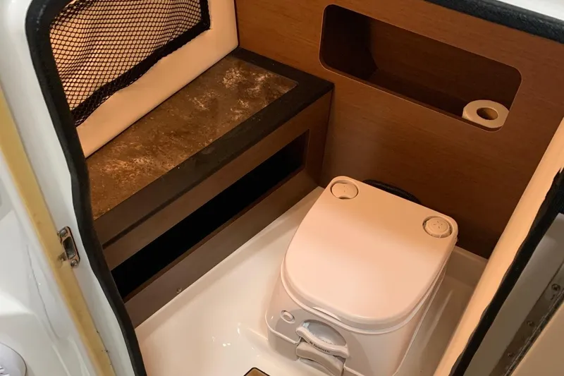 Slide: The Image of Interior of a Sea Ray 240 Sundeck with a toilet and storage space. - 25
