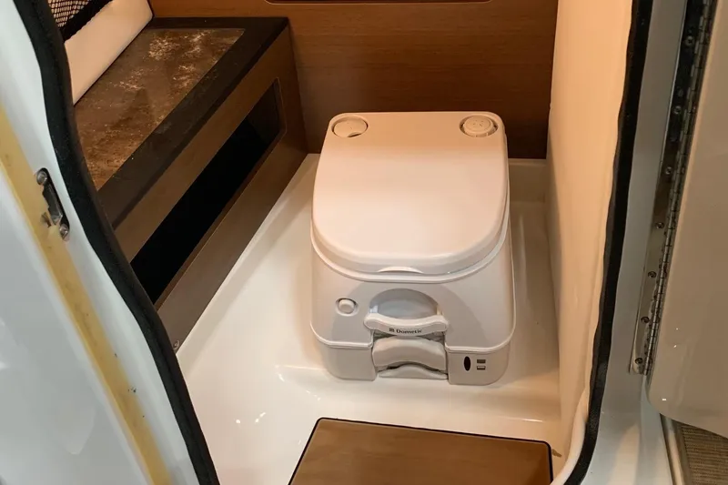 Slide: The Image of A portable boat toilet in a small compartment with wooden walls. - 26