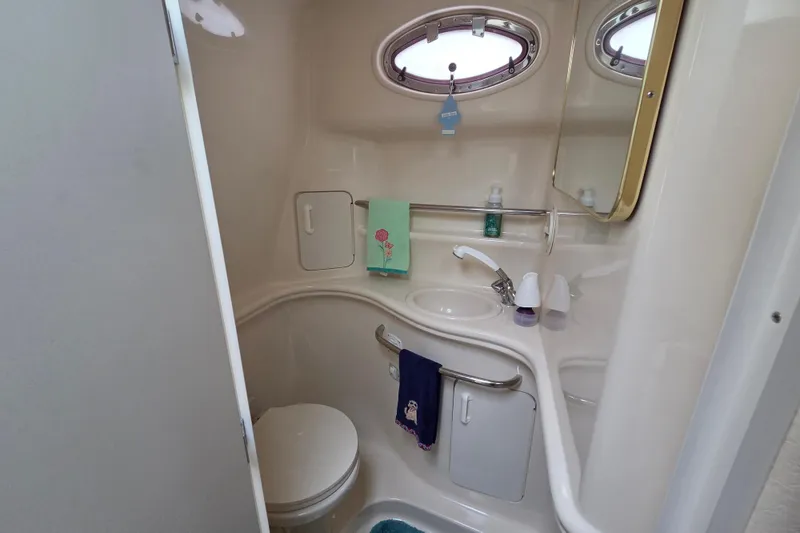 Slide: The Image of 1999 Sea Ray 340 Sundancer bathroom with sink, toilet, and porthole window. - 19