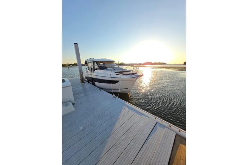 The Image of 2026 Jeanneau NC 895 Series 2 docked at sunset, reflecting on calm water. - 0