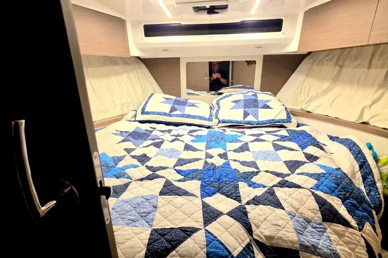 Slide: The Image of Cozy bedroom in 2026 Jeanneau NC 895 Series 2 with blue quilted bedding. - 12