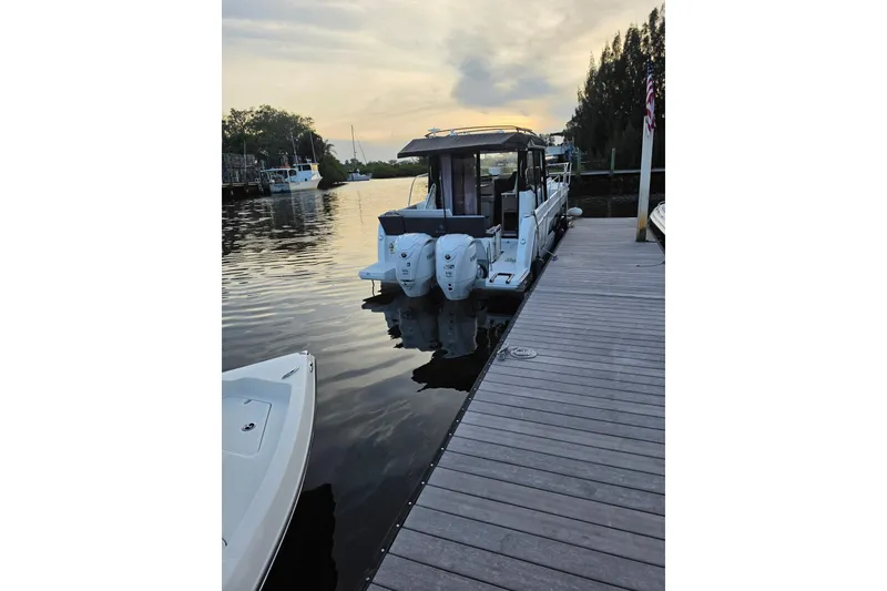 Slide: The Image of 2026 Jeanneau NC 895 Series 2 docked at a serene marina during sunset. - 2
