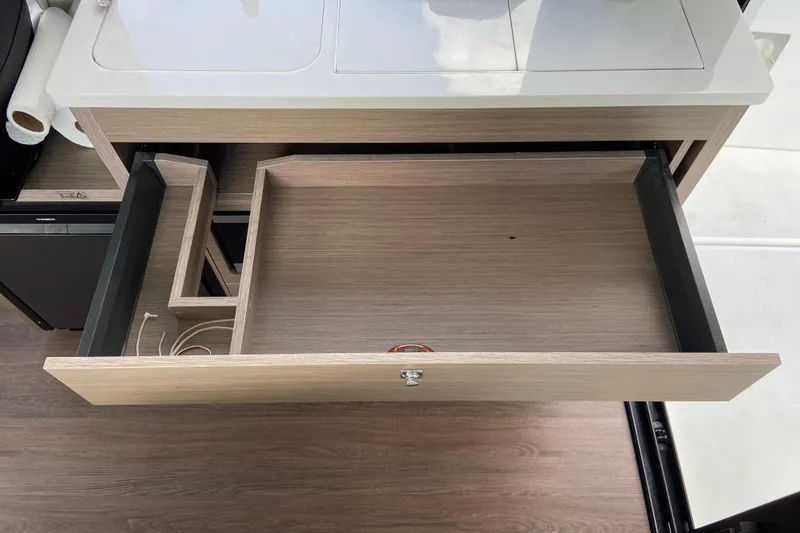 Slide: The Image of Open drawer in a modern boat kitchen with wood finish and storage space. - 31