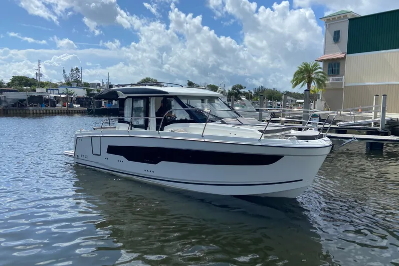 The Image of 2026 Jeanneau NC 895 Series 2 boat docked on a sunny day, with blue skies and clouds. - 0