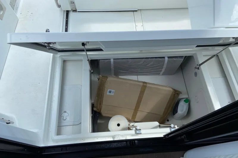 Slide: The Image of Cockpit storage on the Jeanneau NC 895 Series 2 with a box and cleaning supplies. - 13
