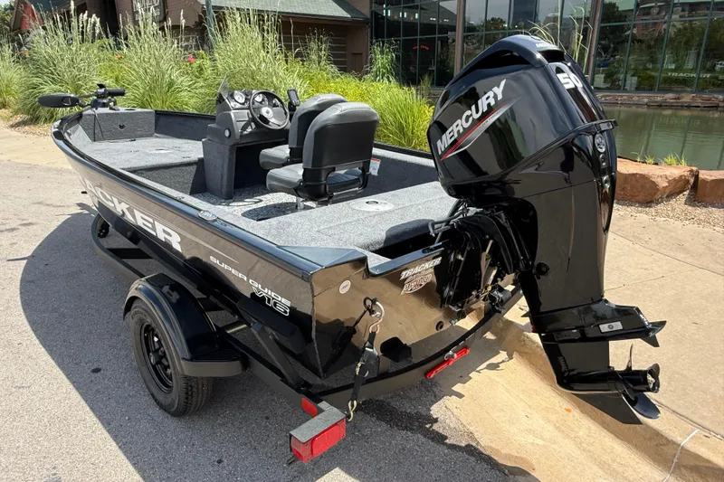 Slide: The Image of 2026 Tracker Super Guide V-16 SC boat with Mercury outboard motor, parked outdoors. - 2