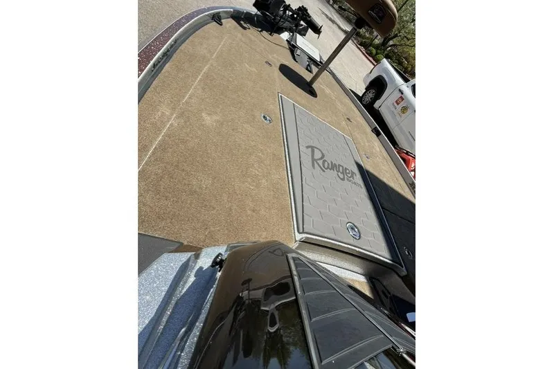 Slide: The Image of 2026 Ranger Z521R Cup-Equipped boat deck with logo, parked near a white vehicle. - 8