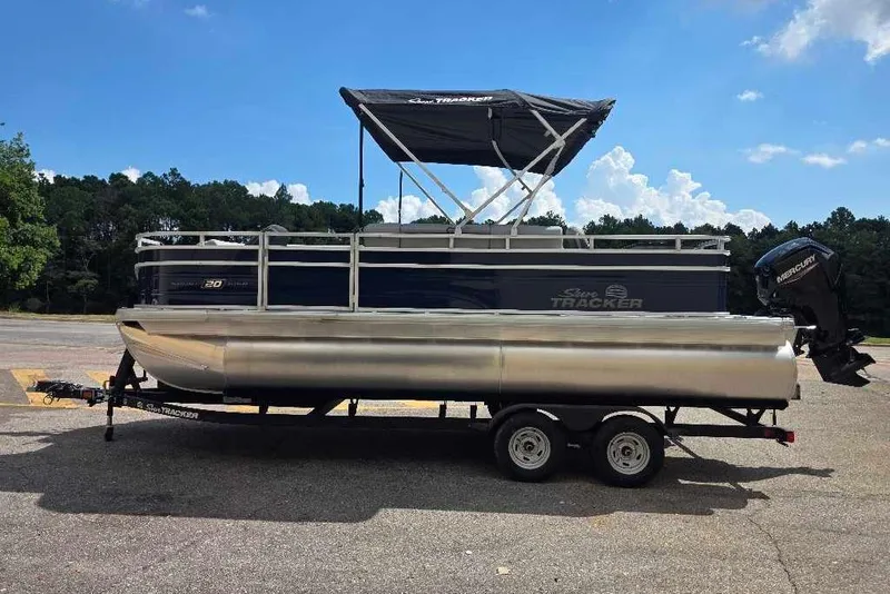 Slide: The Image of 2026 Sun Tracker SportFish 20 DLX pontoon boat on trailer, parked outdoors. - 2