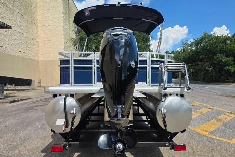 Slide: The Image of 2026 Sun Tracker SportFish 20 DLX pontoon boat with outboard motor, parked outdoors. - 9