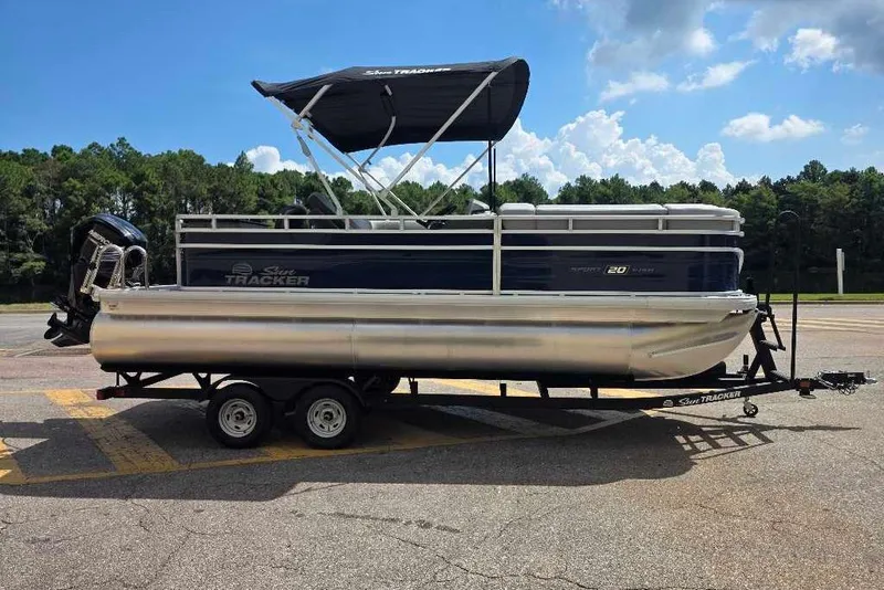 The Image of 2026 Sun Tracker SportFish 20 DLX pontoon boat on trailer, parked outdoors. - 0