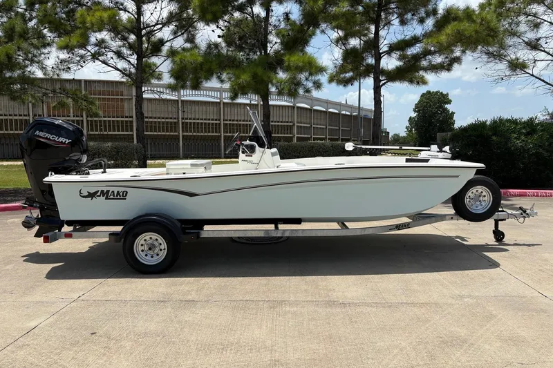 Slide: The Image of 2026 Mako Pro Skiff 17 CC boat on trailer, parked outdoors under trees. - 3