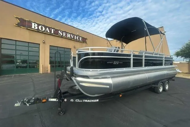 The Image of 2026 Sun Tracker Sportfish 24 XP3 pontoon boat parked outside a boat service center. - 0
