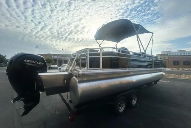 Slide: The Image of 2026 Sun Tracker Sportfish 24 XP3 pontoon boat with Mercury engine, parked under a cloudy sky. - 3