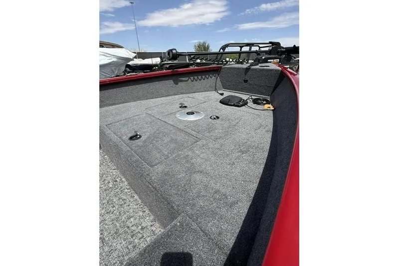 Slide: The Image of 2026 Tracker Super Guide V-16 T boat interior with gray carpet and red trim under blue sky. - 8