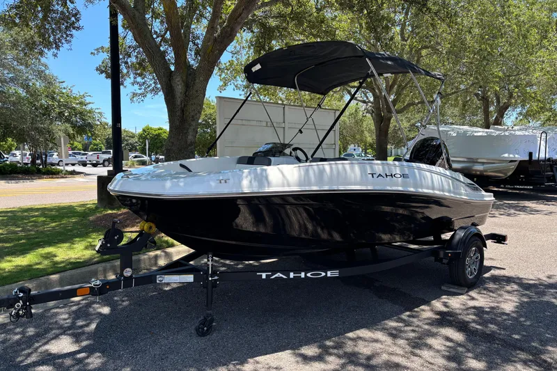The Image of 2026 Tahoe T16 boat on trailer under trees, parked in a sunny outdoor area. - 0