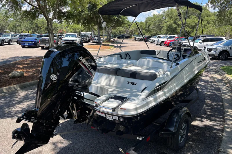 Slide: The Image of 2026 Tahoe T16 boat with Mercury engine, parked outdoors under trees. - 2