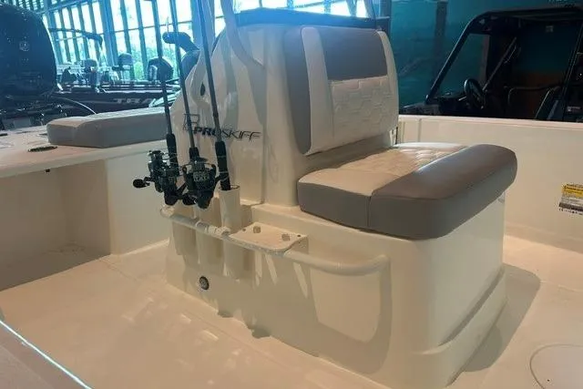 Slide: The Image of 2026 Mako 18 Pro Skiff boat interior with cushioned seating and fishing rod holders. - 9