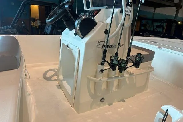 Slide: The Image of 2026 Mako 18 Pro Skiff boat interior with steering console and fishing rod holders. - 8