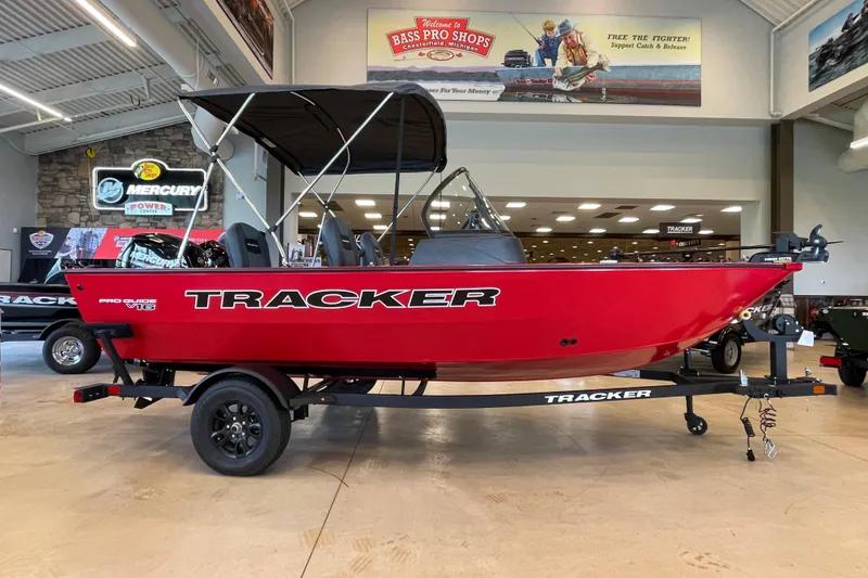 The Image of 2026 Tracker Pro Guide V-16 WT boat in showroom, red exterior, on trailer. - 0