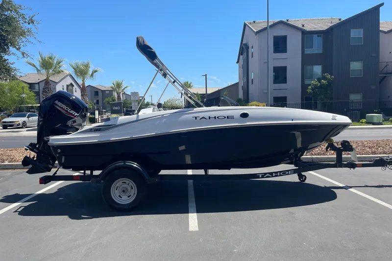 The Image of 2026 Tahoe T16 boat on trailer in parking lot, with Mercury outboard motor. - 0