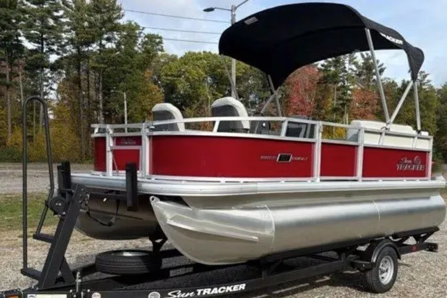 The Image of 2026 Sun Tracker Bass Buggy 16 XL Select pontoon boat on trailer, red and silver design. - 0