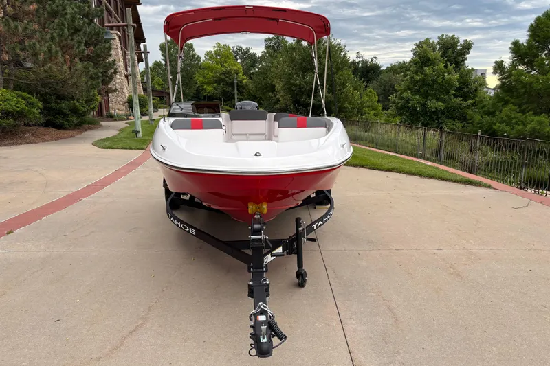 Slide: The Image of 2026 Tahoe T16 boat with red canopy on a trailer, parked outdoors. - 2