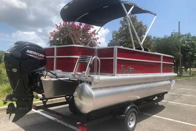 Slide: The Image of 2026 Sun Tracker Party Barge 18 DLX pontoon boat with Mercury outboard motor in a parking lot. - 3