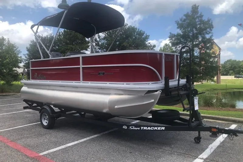 The Image of 2026 Sun Tracker Party Barge 18 DLX pontoon boat on trailer in parking lot. - 0
