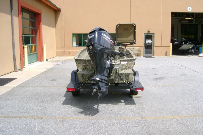 Slide: The Image of 2026 Tracker Grizzly 1650 T Prairie Wings Edition boat with Mercury engine, parked outside a building. - 36