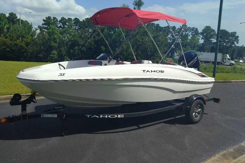 Slide: The Image of 2026 Tahoe T16 boat with red canopy on trailer, parked outdoors. - 1