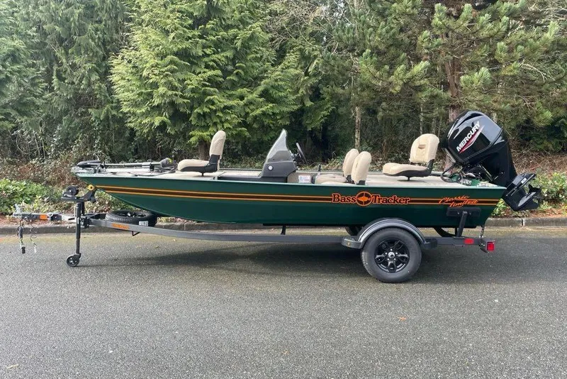 The Image of 2026 Tracker Bass Tracker Classic Limited boat on trailer, surrounded by lush greenery. - 0