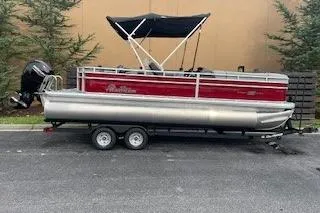 The Image of 2026 Sun Tracker SportFish 22 DLX pontoon boat with canopy on trailer. - 0