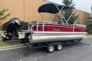 Slide: The Image of 2026 Sun Tracker SportFish 22 DLX pontoon boat on trailer, red and silver design. - 2