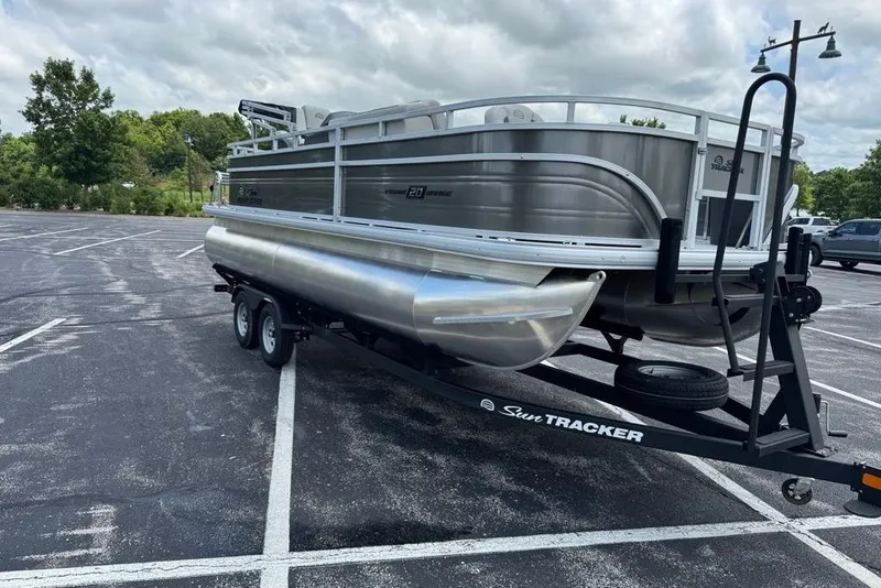 Slide: The Image of 2026 Sun Tracker Fishin' Barge 20 DLX pontoon boat on trailer in parking lot. - 1