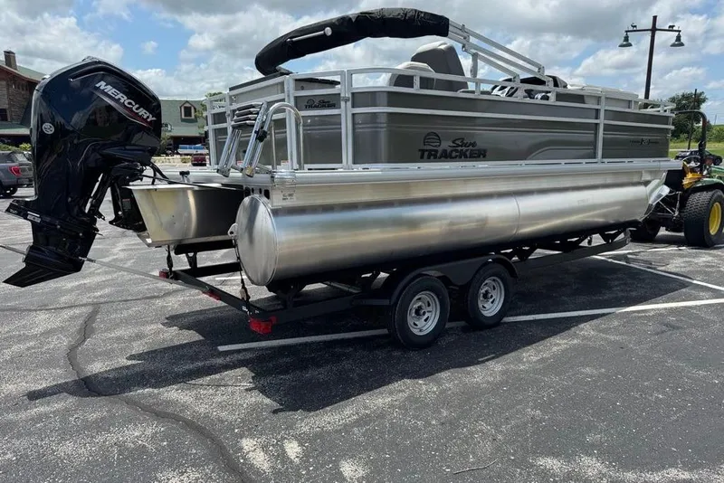 Slide: The Image of 2026 Sun Tracker Fishin' Barge 20 DLX pontoon boat on trailer in parking lot. - 2