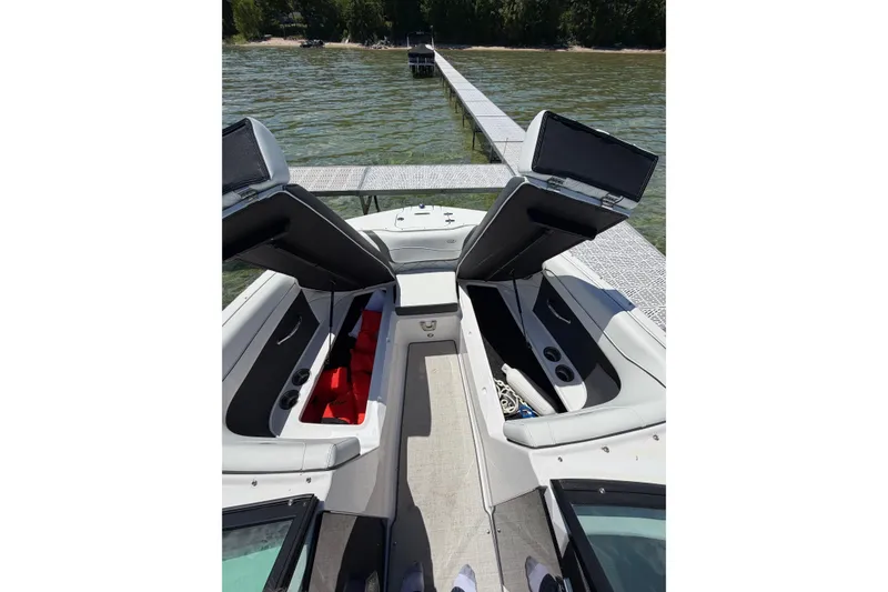 Slide: The Image of 2022 Regal 22 FasDeck boat interior with open storage compartments, docked by a lake. - 14