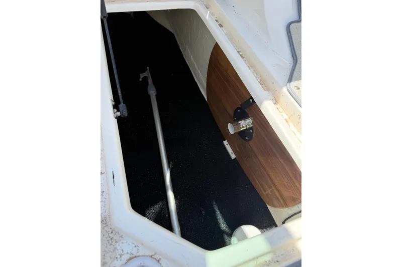 Slide: The Image of Storage compartment of 2022 Regal 22 FasDeck boat with wooden panel and metal pole. - 12