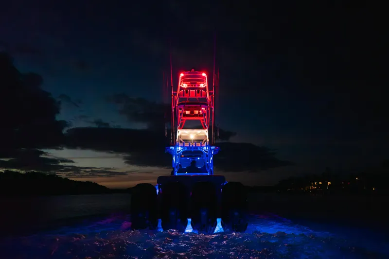 Slide: The Image of 2022 Nor-Tech 392 Super Fish boat illuminated at night with vibrant red and blue lights. - 55