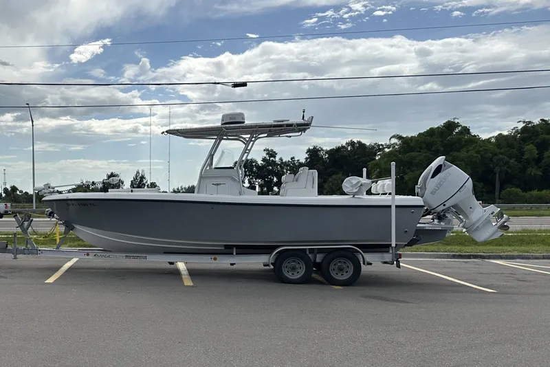 Slide: The Image of 2022 Bluewater 2550 CC boat on trailer, parked in a lot under a cloudy sky. - 1